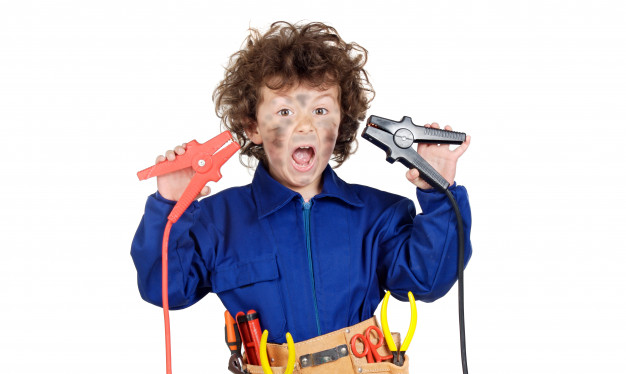 A surprised young engineer holding two car jump-start cables, with a tool belt